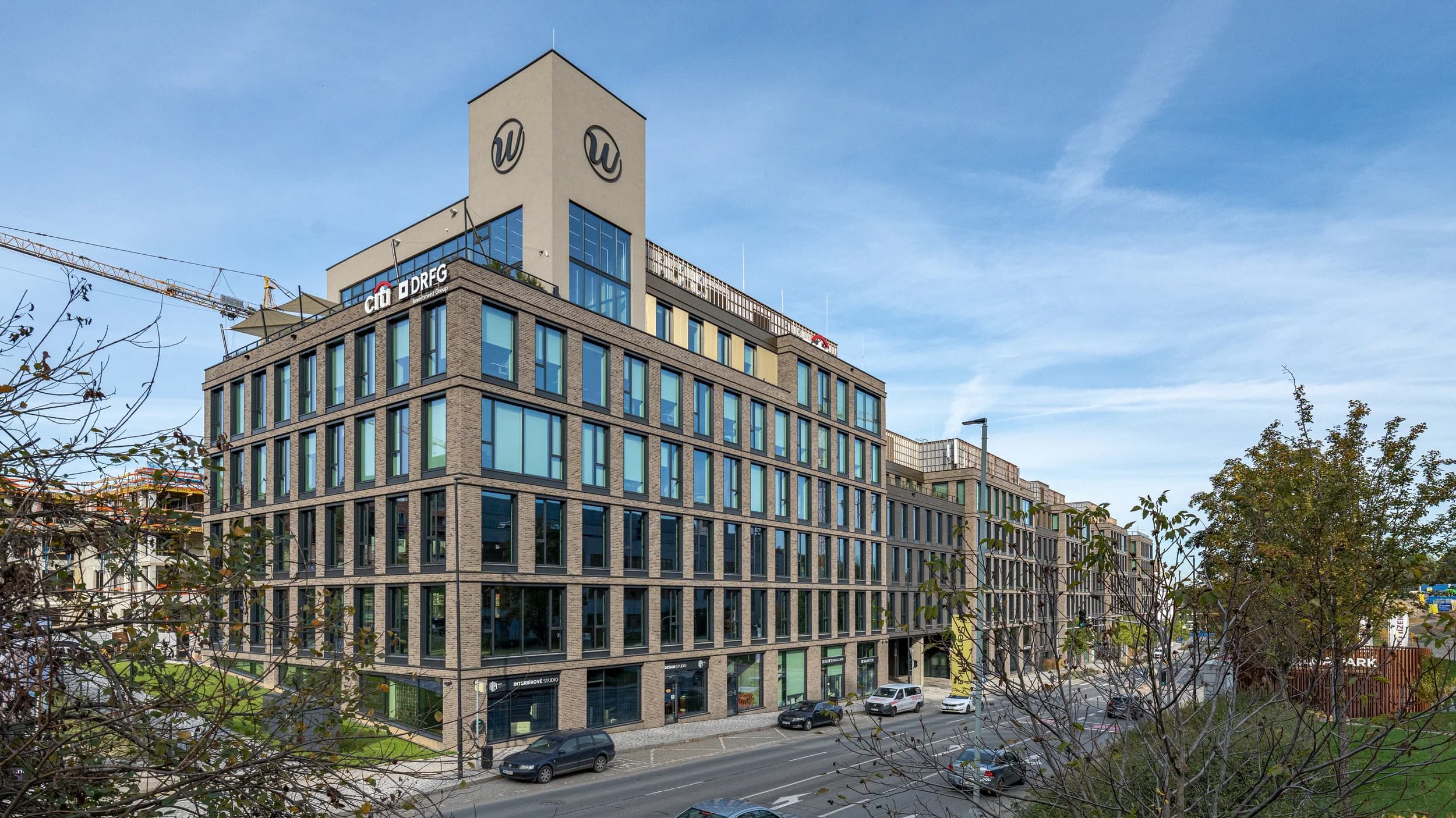 Budova s kancelářemi Citibank v Praze, cihlová fasáda s logem Citi a ulice před vstupem